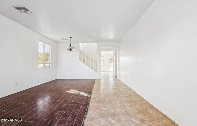 empty room featuring a chandelier and light hardwood / wood-style floors