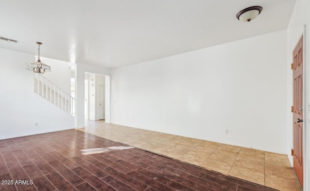 unfurnished room with wood-type flooring and a chandelier