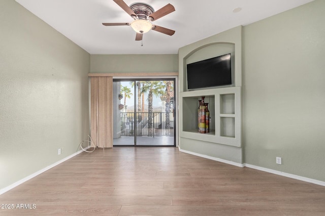 spare room with light wood-type flooring, ceiling fan, and baseboards