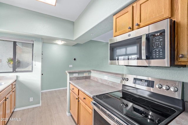 kitchen with stainless steel appliances, light countertops, light wood-style floors, and baseboards