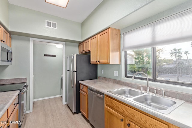 kitchen featuring light wood finished floors, visible vents, stainless steel appliances, light countertops, and a sink