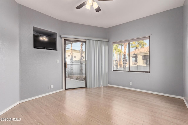 unfurnished room with a ceiling fan, light wood-style flooring, and baseboards