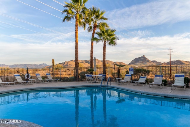 community pool with fence, a mountain view, and a patio