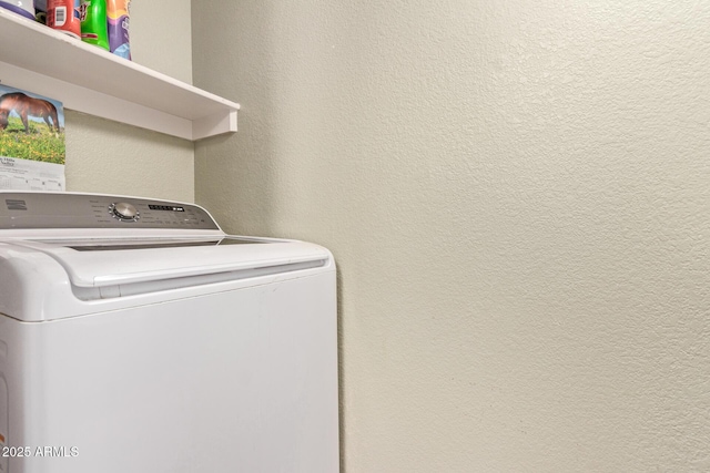 washroom with a textured wall, laundry area, and washer / clothes dryer