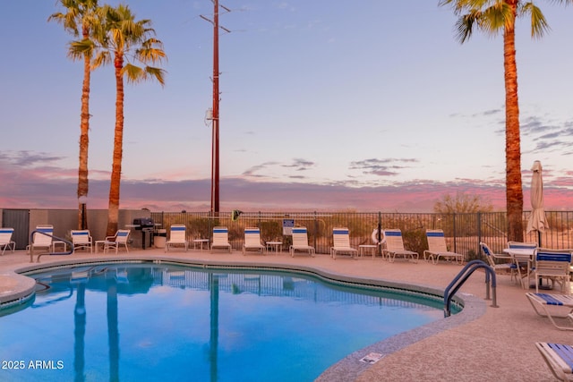 pool at dusk with fence, a community pool, and a patio