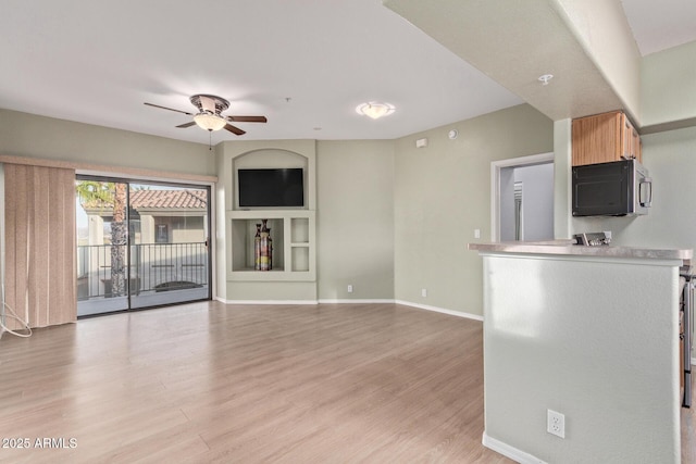 unfurnished living room with light wood-style flooring, baseboards, and a ceiling fan