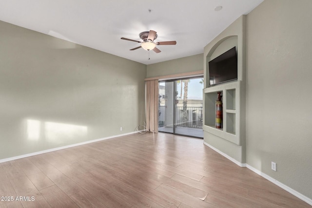 spare room with ceiling fan, light wood finished floors, and baseboards