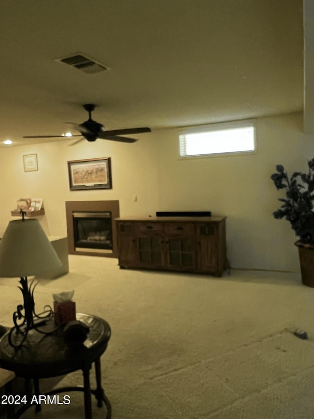 interior space featuring carpet flooring, a ceiling fan, a glass covered fireplace, and visible vents