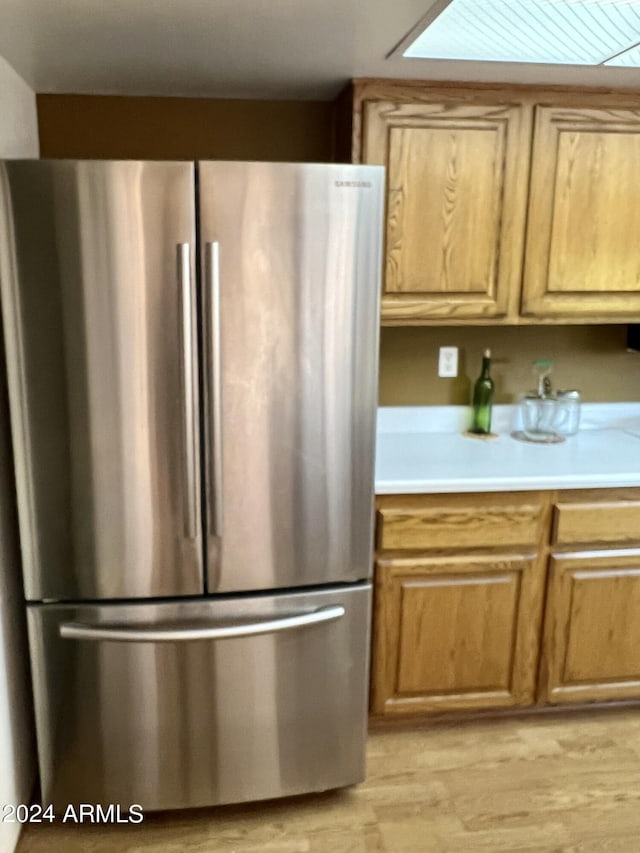 kitchen with light countertops, light wood-type flooring, and freestanding refrigerator
