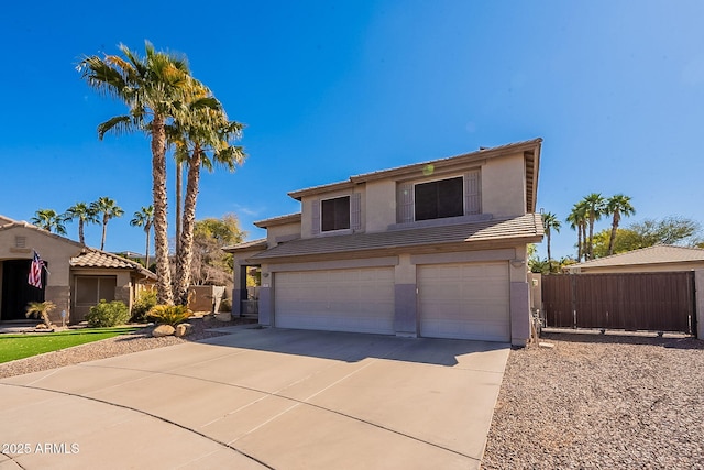 view of front facade with a garage, driveway, a tiled roof, fence, and stucco siding