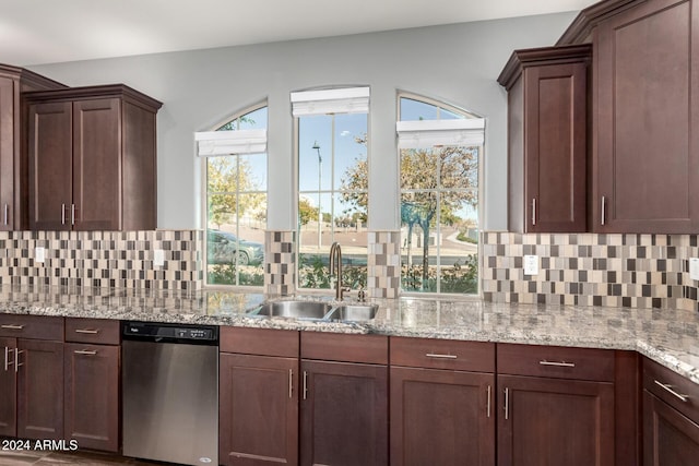 kitchen featuring dark brown cabinetry, sink, light stone counters, stainless steel dishwasher, and backsplash