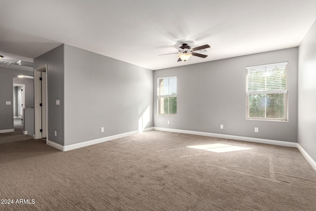 carpeted spare room with ceiling fan and plenty of natural light