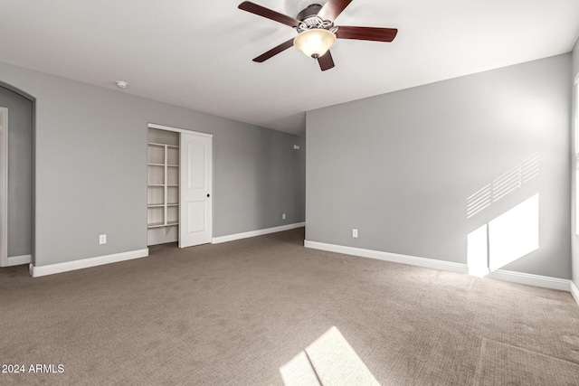 interior space with dark colored carpet, a closet, and ceiling fan