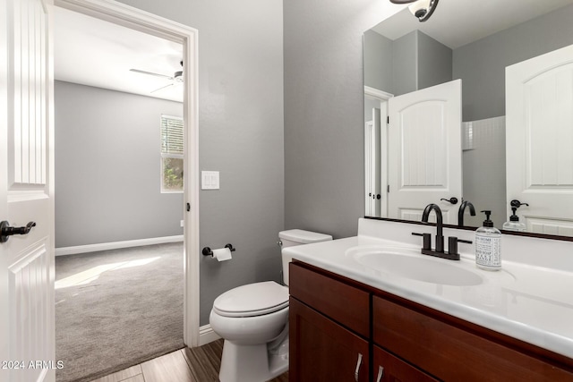 bathroom with hardwood / wood-style floors, vanity, toilet, and ceiling fan