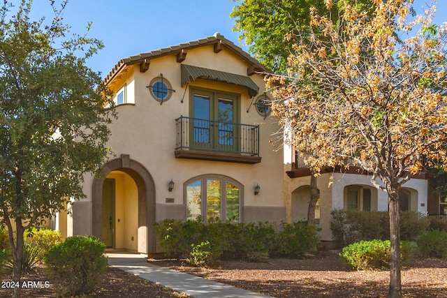 mediterranean / spanish-style home with a balcony and french doors