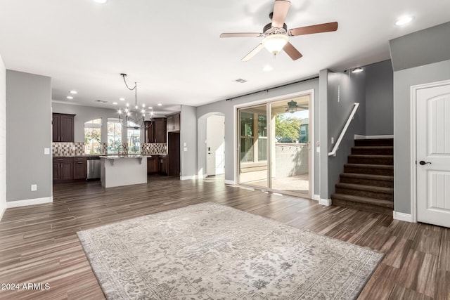 unfurnished living room featuring ceiling fan with notable chandelier and dark hardwood / wood-style flooring