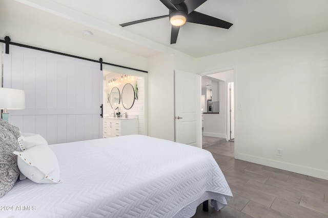 bedroom with ceiling fan, a barn door, and connected bathroom