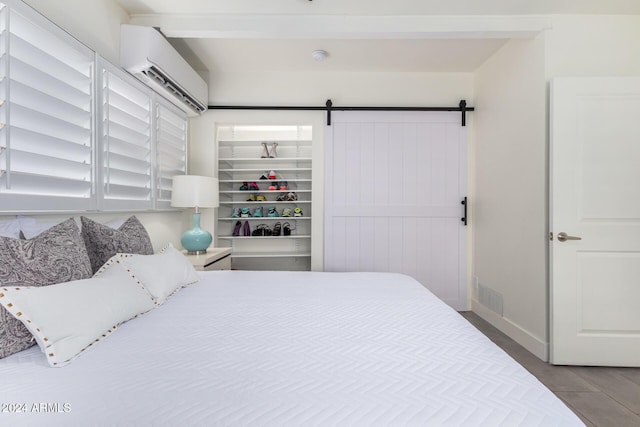 tiled bedroom with a walk in closet, a barn door, and an AC wall unit