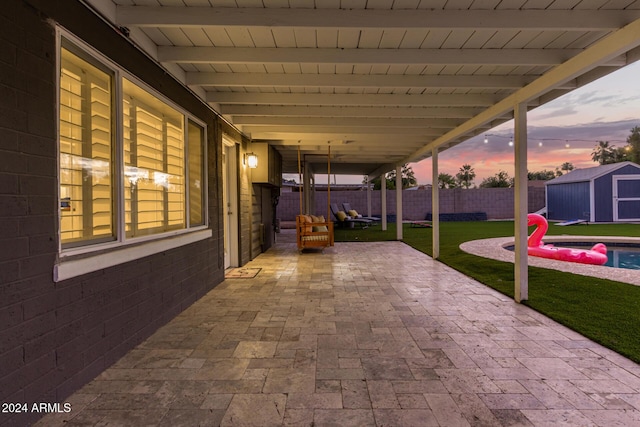 patio terrace at dusk with a lawn and a storage shed