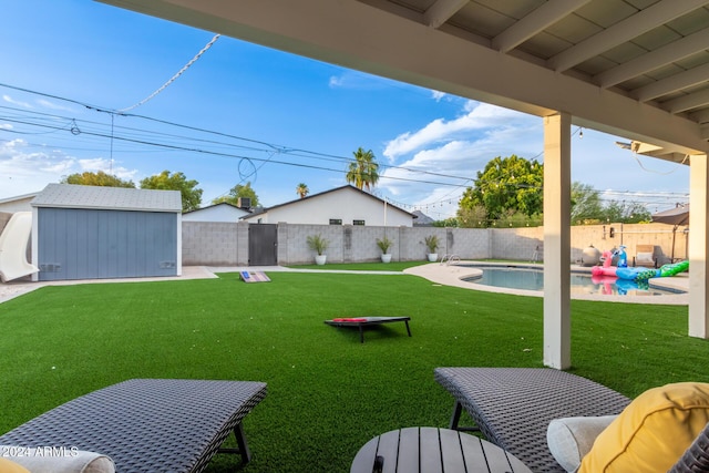 view of yard featuring a fenced in pool and a storage shed