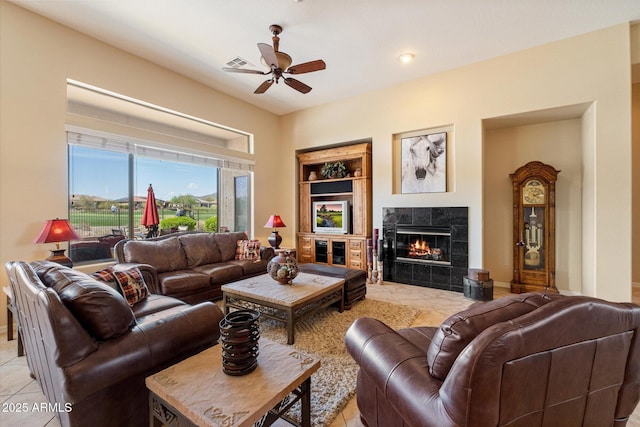 living room with light tile patterned flooring, a tile fireplace, baseboards, visible vents, and ceiling fan