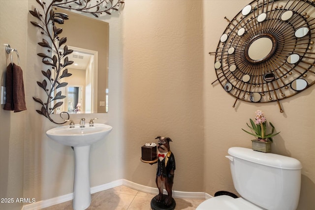 bathroom featuring visible vents, baseboards, toilet, a sink, and tile patterned flooring