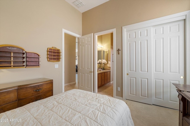 bedroom featuring a closet, ensuite bathroom, visible vents, and light carpet