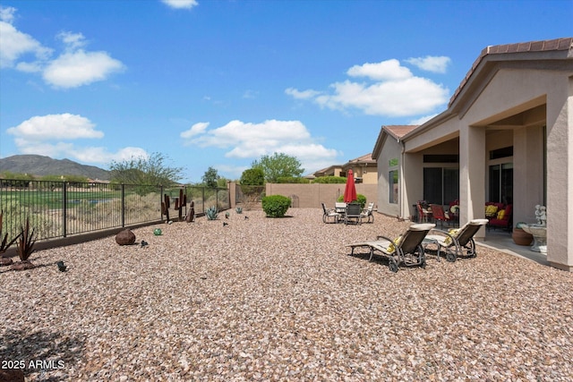 view of yard with a mountain view, a fenced backyard, and a patio area