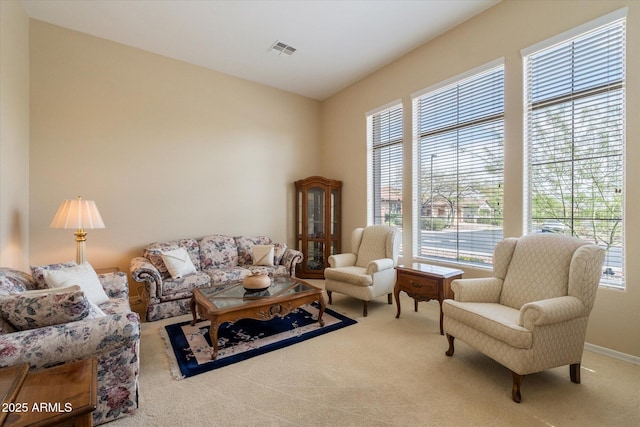 living room featuring baseboards, carpet flooring, a wealth of natural light, and visible vents