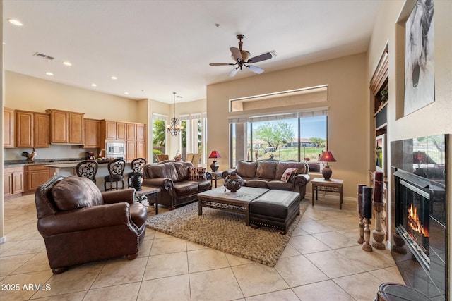 living area with light tile patterned flooring, visible vents, a fireplace, recessed lighting, and ceiling fan with notable chandelier
