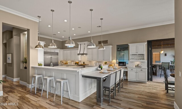 kitchen with stainless steel built in refrigerator, white cabinetry, and a breakfast bar area