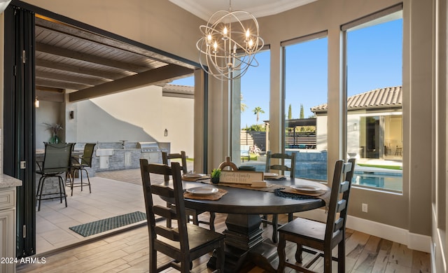 dining room featuring light wood-style floors, a chandelier, plenty of natural light, and beamed ceiling