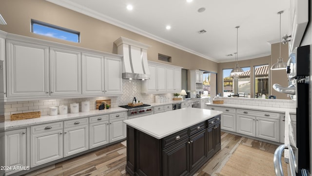 kitchen with visible vents, white cabinets, ornamental molding, wall chimney exhaust hood, and stainless steel gas stovetop