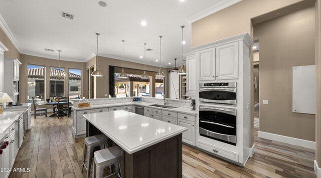 kitchen with a breakfast bar area, kitchen peninsula, decorative light fixtures, and light wood-type flooring