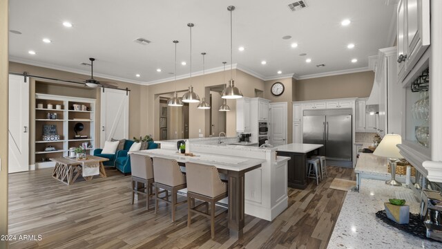 kitchen with a barn door, visible vents, appliances with stainless steel finishes, and a kitchen breakfast bar