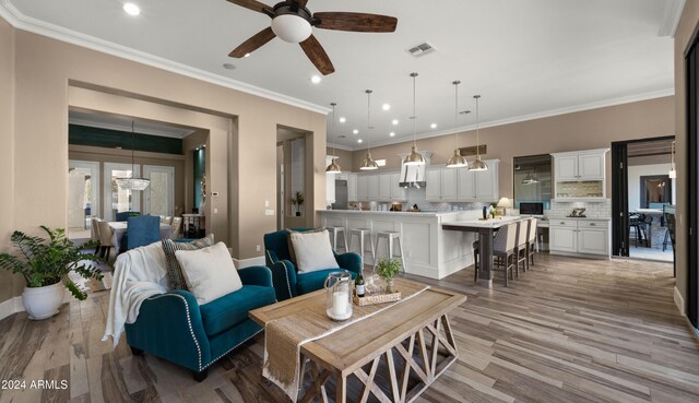 living room with baseboards, visible vents, wood finished floors, crown molding, and recessed lighting