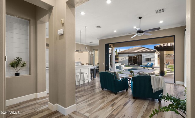 living room with ornamental molding, visible vents, and wood finished floors