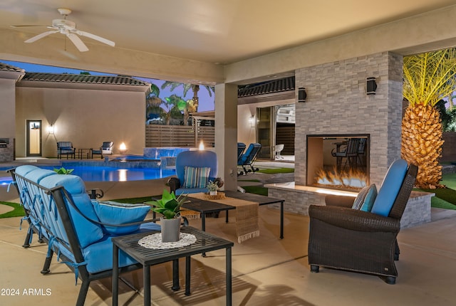 patio terrace at dusk with an outdoor living space with a fireplace and ceiling fan