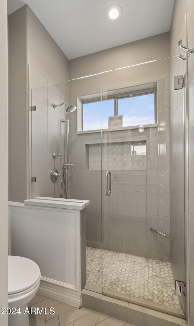 full bath with a stall shower, toilet, and tile patterned floors