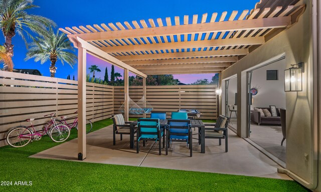 patio terrace at dusk featuring outdoor dining area, a fenced backyard, and a pergola