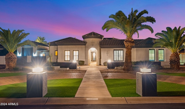 mediterranean / spanish house featuring a tile roof, a front yard, and stucco siding