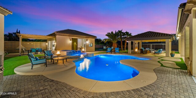 pool at dusk with an in ground hot tub, a gazebo, and a patio