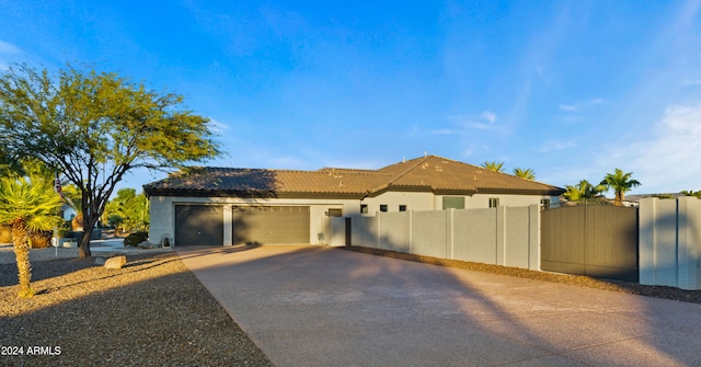 mediterranean / spanish house with concrete driveway, a tile roof, an attached garage, fence, and stucco siding