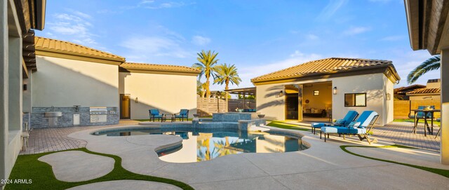 view of swimming pool with a pool with connected hot tub, a patio area, fence, and area for grilling