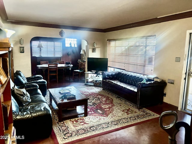 living area with arched walkways, plenty of natural light, and ornamental molding