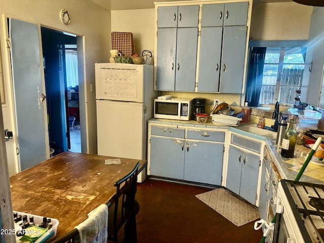 kitchen with white appliances, gray cabinetry, decorative backsplash, tile counters, and a sink