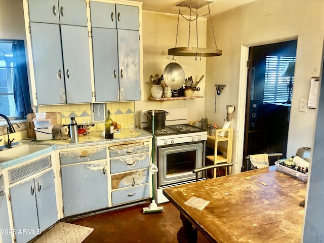 kitchen featuring backsplash, concrete floors, tile counters, white range with gas stovetop, and a sink