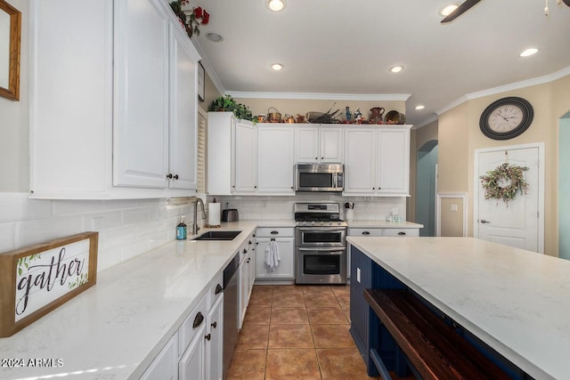 kitchen with light stone countertops, white cabinetry, sink, stainless steel appliances, and dark tile patterned flooring