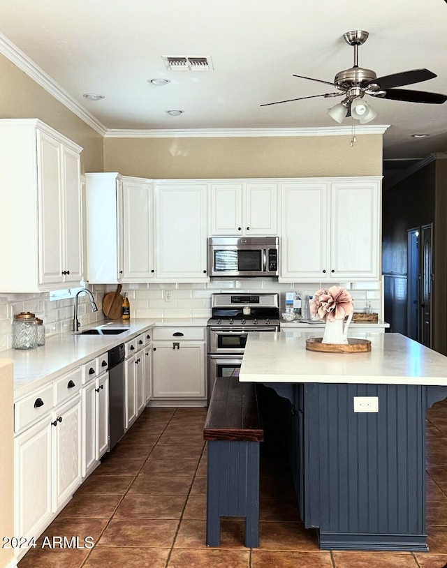 kitchen featuring decorative backsplash, appliances with stainless steel finishes, sink, a center island, and white cabinetry