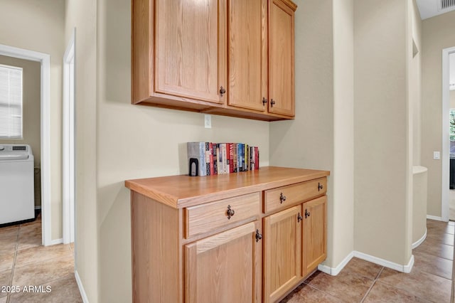 hallway featuring light tile patterned floors, baseboards, and washer / clothes dryer